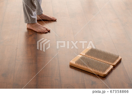 Young active barefoot man in sportspants standing on wooden floor by yoga pads 67358866