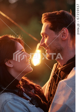 Evening light between young affectionate dates looking at one another outdoors Evening light between young affectionate dates looking at one another outdoors 67359437