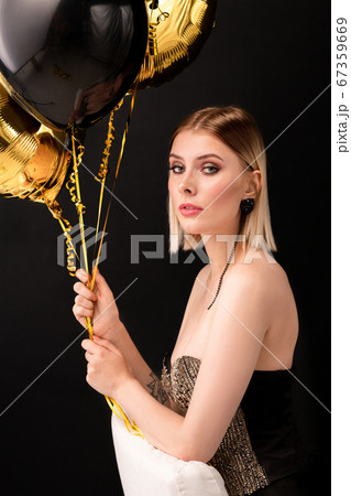 Blond elegant female with black and golden color balloons looking at you Blond elegant female with black and golden color balloons looking at you 67359669