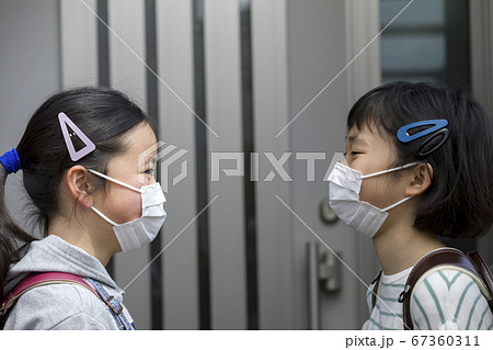 マスク姿で向かい合う小学生 会話 通学 登校の写真素材