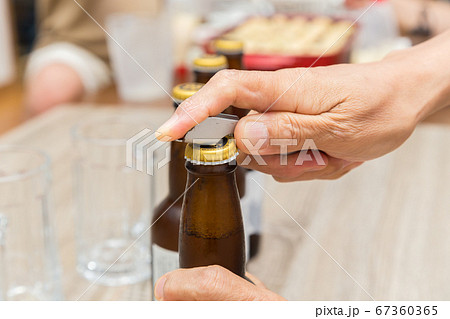 瓶ビールを開けるシニア男性の手元 瓶ビールを開けるシニア男性の手元 67360365