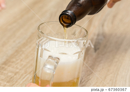 瓶ビールをビールジョッキへ注ぐ手元 67360367