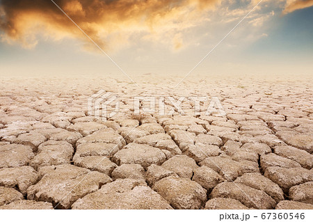 A view of a dry land, with orange clouds and sunset backgraund. Summer season drought farmlands. Global warming and climate change concept. 67360546