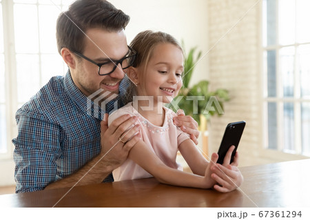 Smiling father wearing glasses hugging little daughter, taking selfie together 67361294