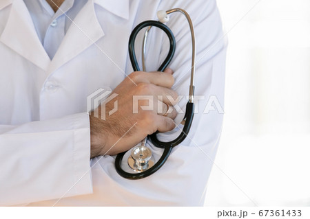 Close up male doctor wearing white uniform holding stethoscope Close up male doctor wearing white uniform holding stethoscope 67361433