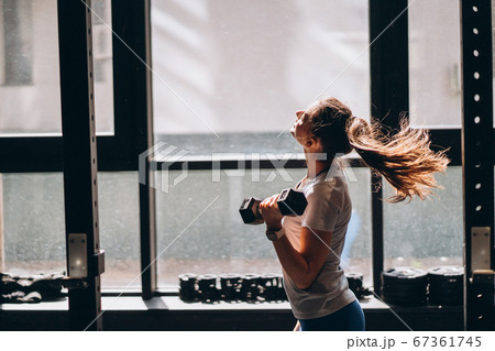 Slender athletic girl performs physical exercises with dumbbells. 67361745