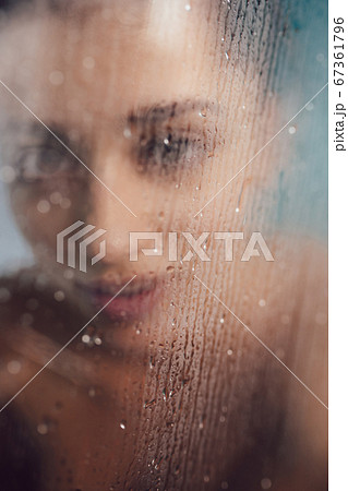 Beautiful woman behind the glass with water drops. Beautiful woman behind the glass with water drops. 67361796