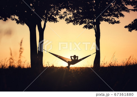 People on vacation. A girl's silhouette in a hammock between trees. People on vacation. A girl's silhouette in a hammock between trees. 67361880