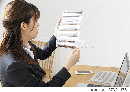 机でフィルムネガシートを見て写真を確認する女性 67364478