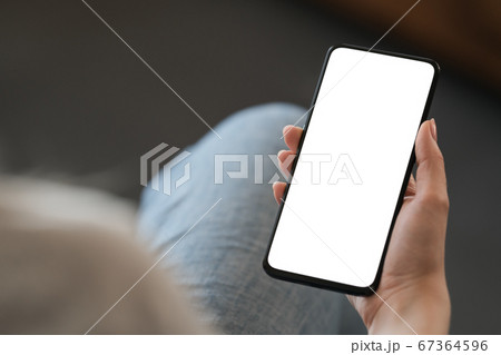 Young woman hold smarphone with white screen while sitting in a chair Young woman hold smarphone with white screen while sitting in a chair 67364596