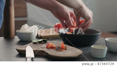 man take chopped tomatoes on olive wood board man take chopped tomatoes on olive wood board 67364729