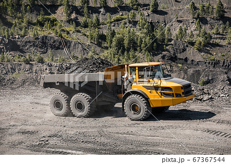 Large quarry dump truck. Loading the rock in dumper. Loading coal into body truck. Production useful minerals. Mining truck mining machinery, to transport coal from open-pit excavator work 67367544