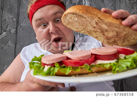shocked fat man is opening big sandwich 67368558