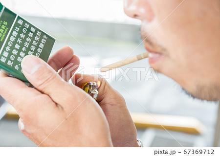 タバコの火をつける男性の手元 67369712