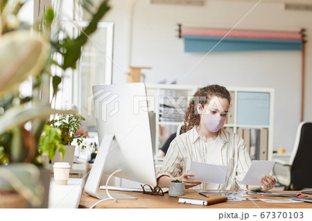 Young Woman Wearing Mask While Working in Office 67370103