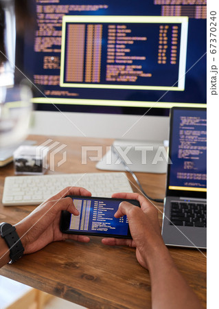 Mobile App Developer Holding Smartphone at Workplace Close Up Mobile App Developer Holding Smartphone at Workplace Close Up 67370240