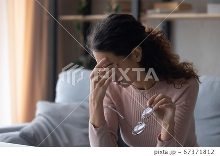 Unwell young woman take off glasses suffering from migraine 67371812