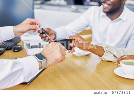 close-up photo of salesman's hand giving business card and keys to buyers 67373311