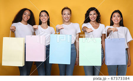 Happy Girls Showing Shopper Bags Standing Over Yellow Background, Mockup Happy Girls Showing Shopper Bags Standing Over Yellow Background, Mockup 67373384
