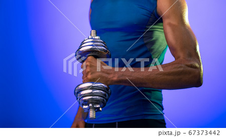 Unrecognizable African Sporty Guy Exercising With Dumbbell On Blue Background Unrecognizable African Sporty Guy Exercising With Dumbbell On Blue Background 67373442
