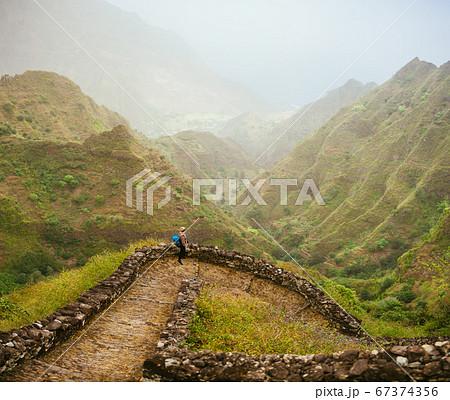 Female tourist enjoying Paul valley with gorgeous panorama view over high mountain ranges and deep valley 67374356