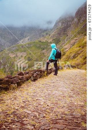 Active vacation tourism. Man enjoying impressive mountainscape. Arid canyon valley extend far below. Santo Antao, Cabo Verde 67374429