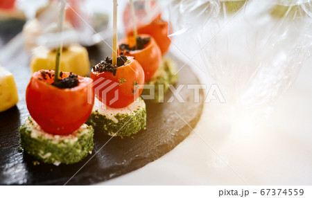 stuffed little tomatoes on a black tray Canapes Catering 67374559