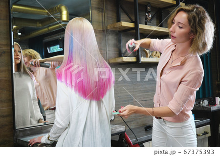 Beautiful blond girl with colored pink hair in a hairdressing salon. 67375393