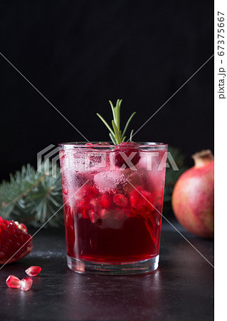 Pomegranate Christmas cocktail with rosemary, champagne, club soda on black table. Close up. 67375667