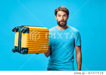 A guy with a suitcase in his hand looks at the camera  67377519