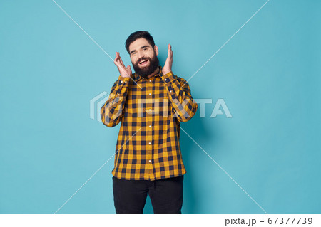 A guy with a bushy beard in a plaid shirt is laughing  67377739