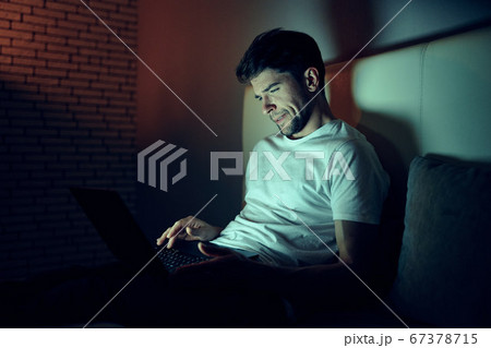 A man indoors at night prints text on a laptop A man indoors at night prints text on a laptop 67378715