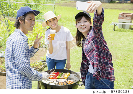 バーベキュー中スマホで記念撮影をする男女　バーベキューイメージ 67380183
