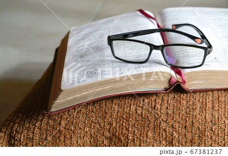 Open bible on a pilllow, with reading glasses on 67381237