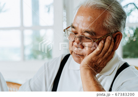 Stressed senior Asian male in glasses leaning on hand and pondering about problems at home. Elderly man thinking about something Stressed senior Asian male in glasses leaning on hand and pondering about problems at home. Elderly man thinking about something 67383200