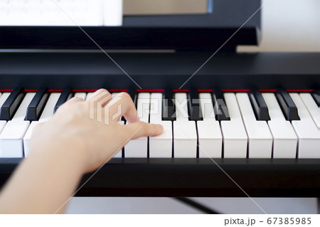 楽譜を見ながら電子ピアノを弾く女性の上半身 67385985