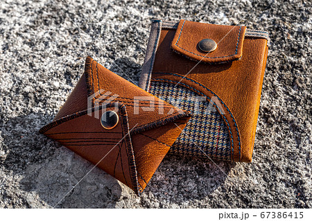 Two handmade wallets of brown leather on stone background. Fashion accessory. Two handmade wallets of brown leather on stone background. Fashion accessory. 67386415