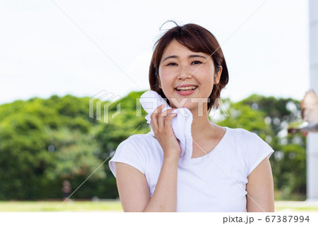 汗を拭く女性 67387994