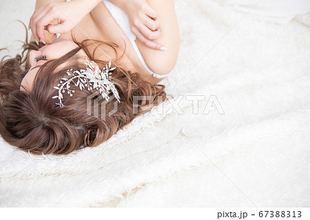 白いベッドの上にドレスを着たきれいな女性が寝ている　woman bed beauty 67388313