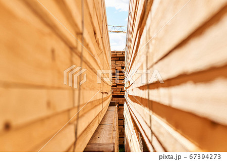 view of a lumber yard between stacks of boards view of a lumber yard between stacks of boards 67394273