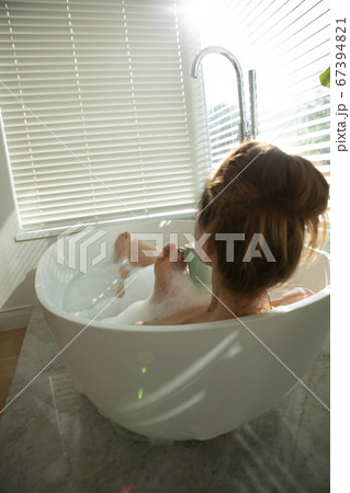 Rear view of woman with coffee cup relaxing in a bathtub Rear view of woman with coffee cup relaxing in a bathtub 67394821