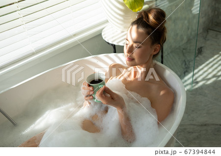 Woman with coffee cup relaxing in a bathtub Woman with coffee cup relaxing in a bathtub 67394844