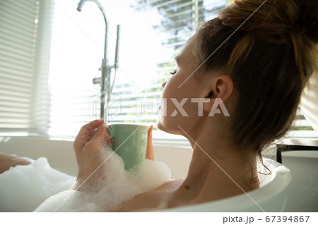 Woman with coffee cup relaxing in a bathtub Woman with coffee cup relaxing in a bathtub 67394867