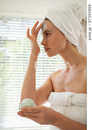 Woman applying face pack in bathroom 67394868