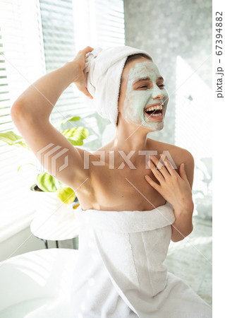 Woman with face pack smiling in bathroom Woman with face pack smiling in bathroom 67394882