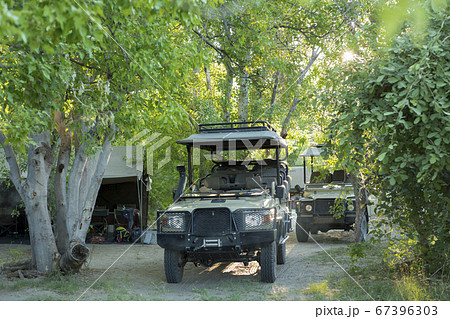 Safari vehicles under the trees in a wildlife reserve camp. Safari vehicles under the trees in a wildlife reserve camp. 67396303