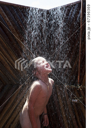 A five year old boy in an outdoor shower at a wildlife reserve camp. 67396369