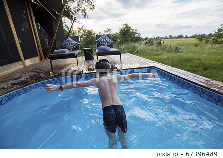 A six year old boy diving into a swimming pool at a tented camp 67396489