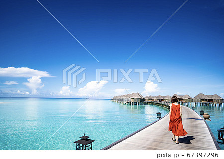 モルジブの水上コテージへ向かう赤いドレスの女性1 67397296