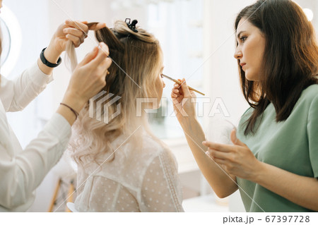 Professional stylist and makeup artist doing makeup and style hair for young woman Professional stylist and makeup artist doing makeup and style hair for young woman 67397728